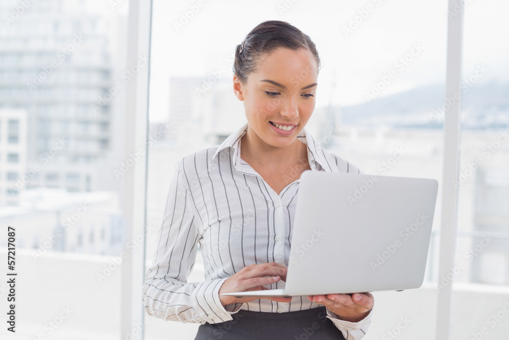 Businesswoman standing and typing on a laptop