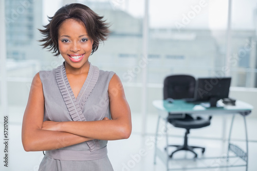 Free Download Smiling businesswoman standing in office and crossing her arms - GFXLoad