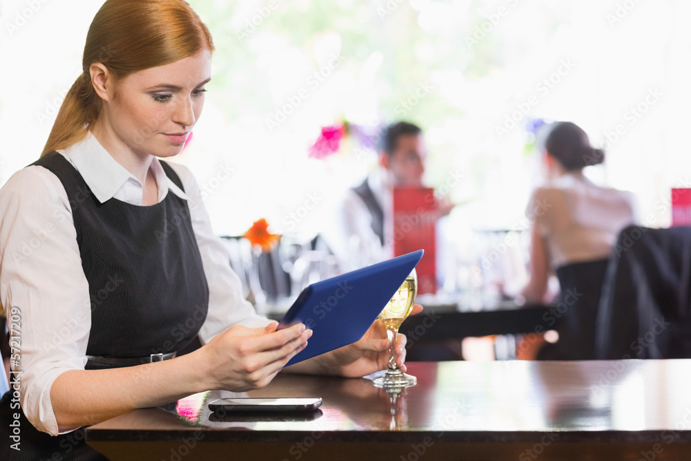 Businesswoman looking at tablet screen while holding wine glass Businesswoman looking at tablet screen while holding wine glass
