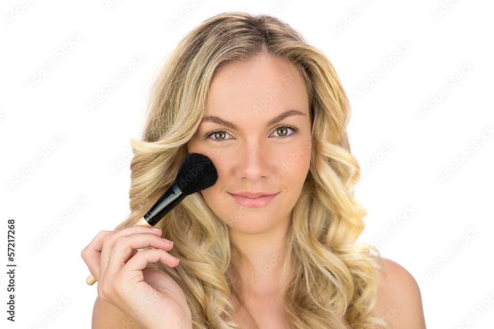 Smiling curly haired blonde using powder brush Smiling curly haired blonde using powder brush