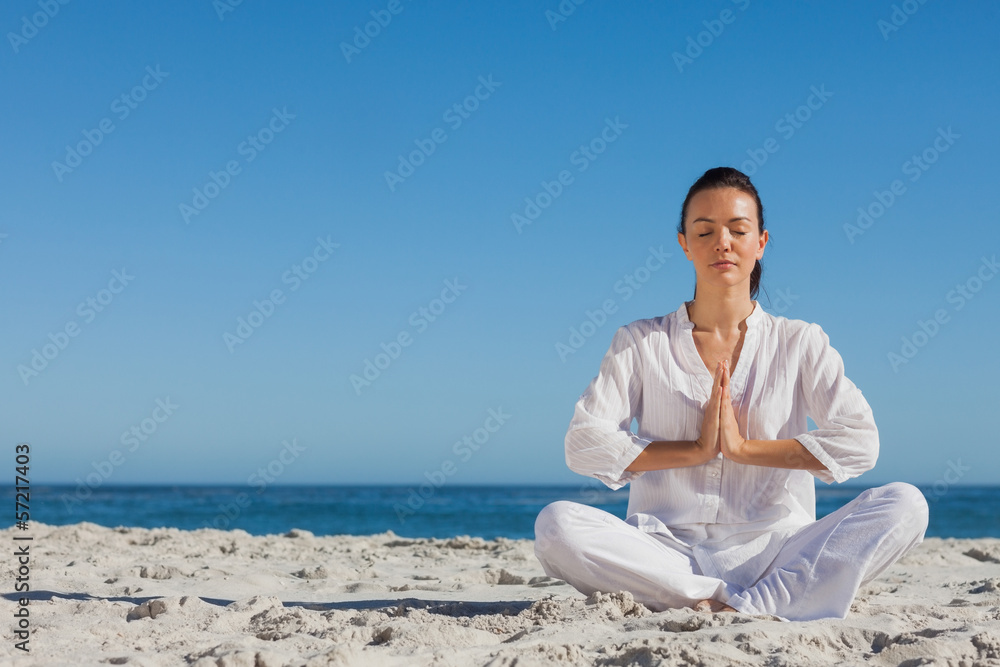 Peaceful woman practicing yoga on the beach