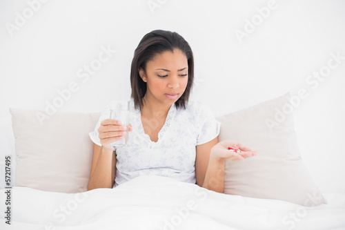 Worried young dark haired model taking medication