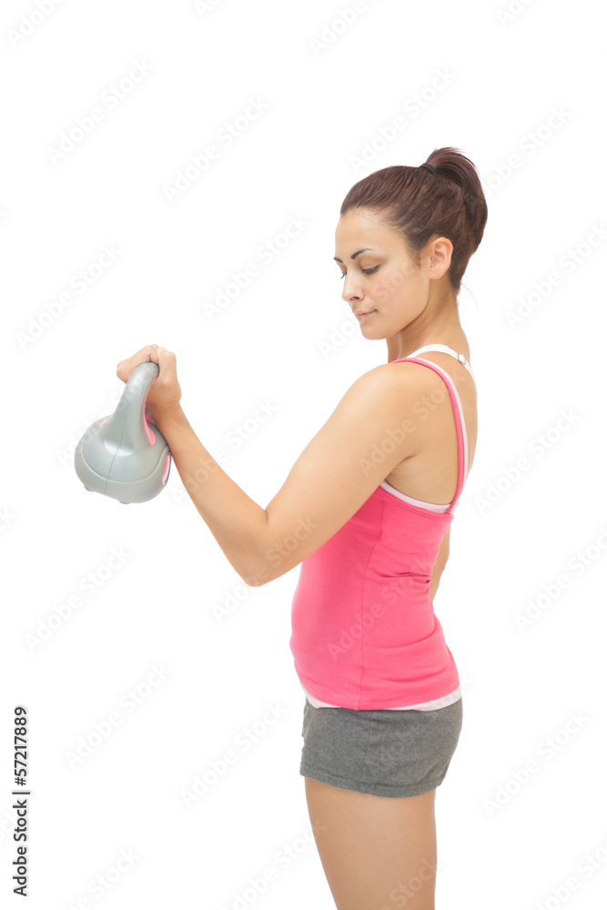 Peaceful sporty brunette holding grey and pink kettlebell Peaceful sporty brunette holding grey and pink kettlebell