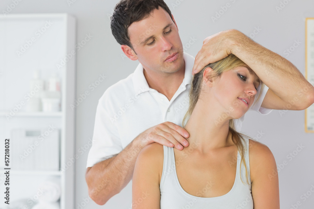 Fototapeta premium Attractive physiotherapist examining patients neck