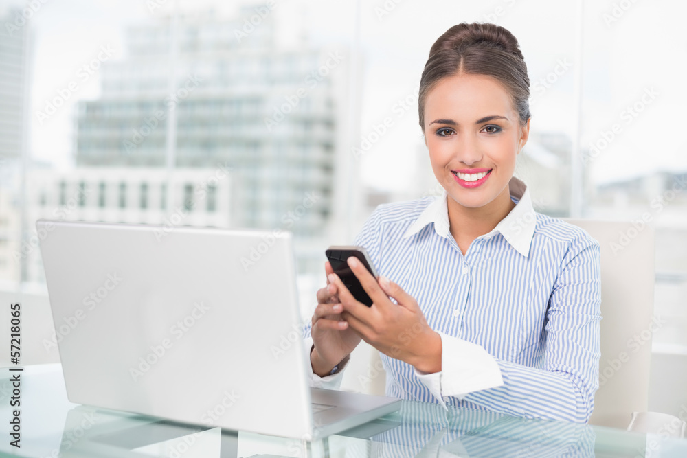 Smiling brunette businesswoman holding smartphone Smiling brunette businesswoman holding smartphone