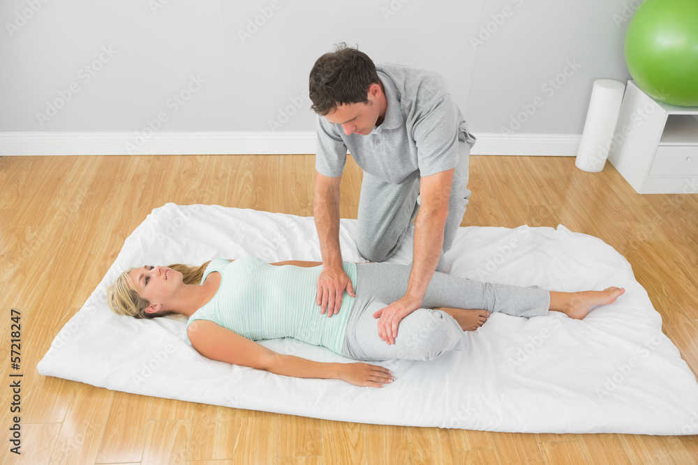 Physiotherapist treating patient on a mat on the floor Physiotherapist treating patient on a mat on the floor