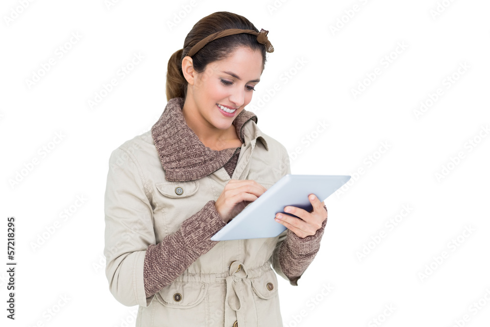 Smiling cute brunette in winter fashion using tablet
