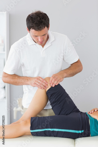 Physiotherapist examining knee of a patient