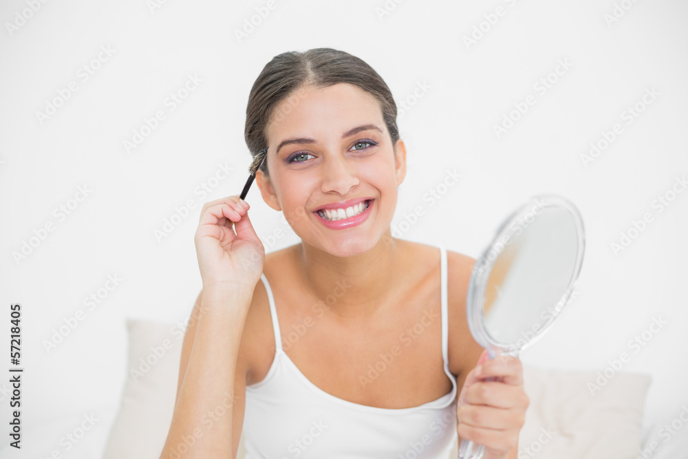 Joyful young brown haired model in white pajamas plucking her ey Joyful young brown haired model in white pajamas plucking her ey