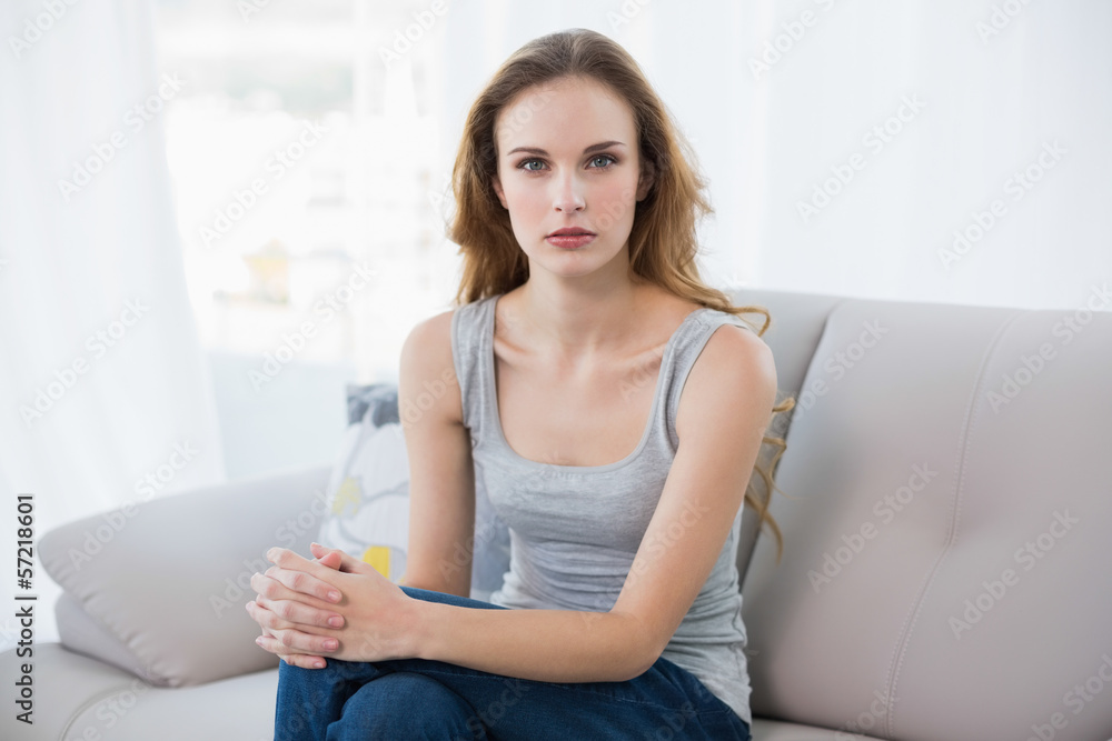 Stern young woman sitting on couch Stern young woman sitting on couch