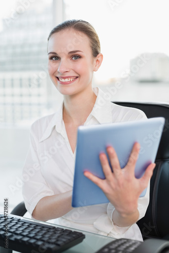 Smiling businesswoman sitting at desk holding tablet pc Free Download Smiling businesswoman sitting at desk holding tablet pc - GFXLoad