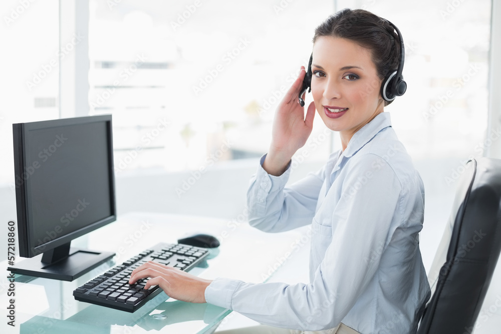 Pretty stylish brunette operator using a computer and answering Pretty stylish brunette operator using a computer and answering