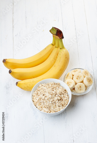 Bowl of oat flakes with sliced banana on wooden table