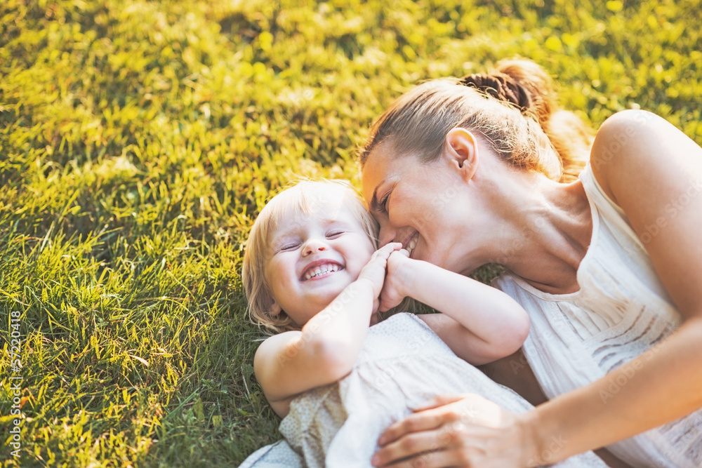 Happy mother and baby laying on meadow Happy mother and baby laying on meadow