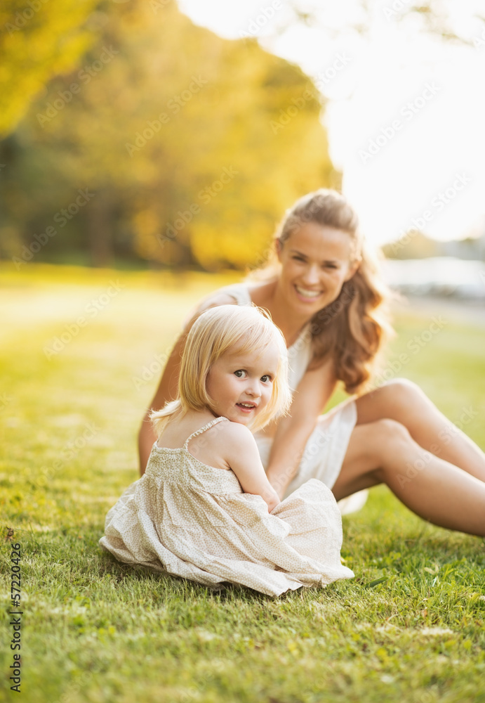 Happy mother and baby sitting on meadow in park Happy mother and baby sitting on meadow in park