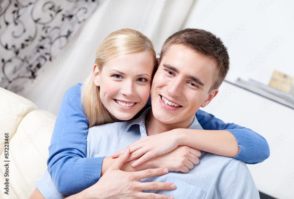 Happy couple sits on the sofa hugging each other Happy couple sits on the sofa hugging each other
