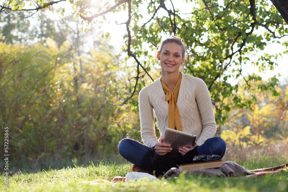 woman sitting on bedding on green grass with tablet pc woman sitting on bedding on green grass with tablet pc