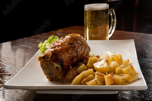 stinco di maiale con patate al forno e birra photo