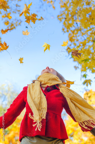 Happy woman throwing autumn leaves. Place for text