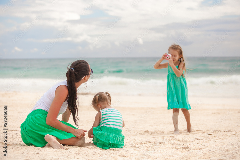 Little girl photographs her mother with sister on the beach Little girl photographs her mother with sister on the beach