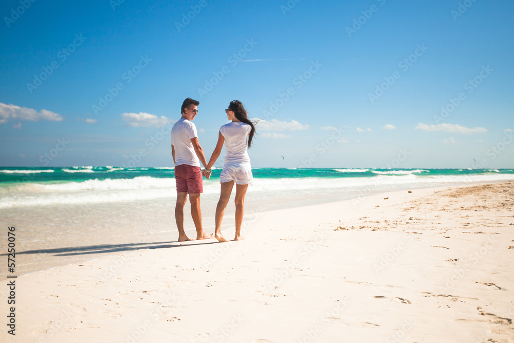 Back view of young couple in love walking at tropical white