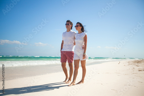 Young romantic couple walking on exotic beach in sunny day