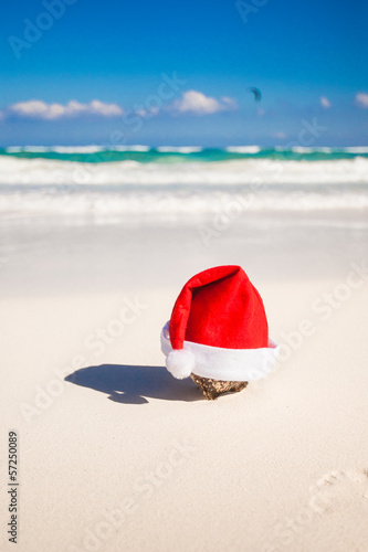 Santa Claus hat on the white sandy coast