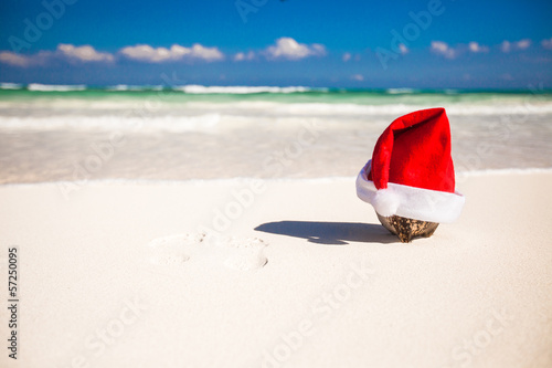 Santa hat at coconut on a white sandy beach