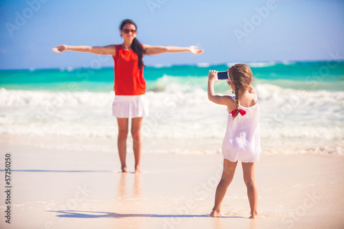 Little girl photographs her mother on the beach