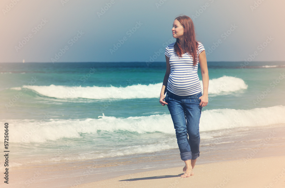 Young pregnant woman walking at the beach