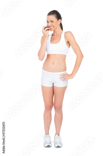 Happy woman in sportswear eating red apple © lightwavemedia