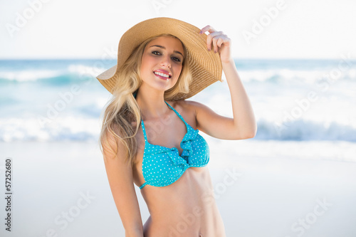 Cheerful sexy blonde in bikini wearing straw hat