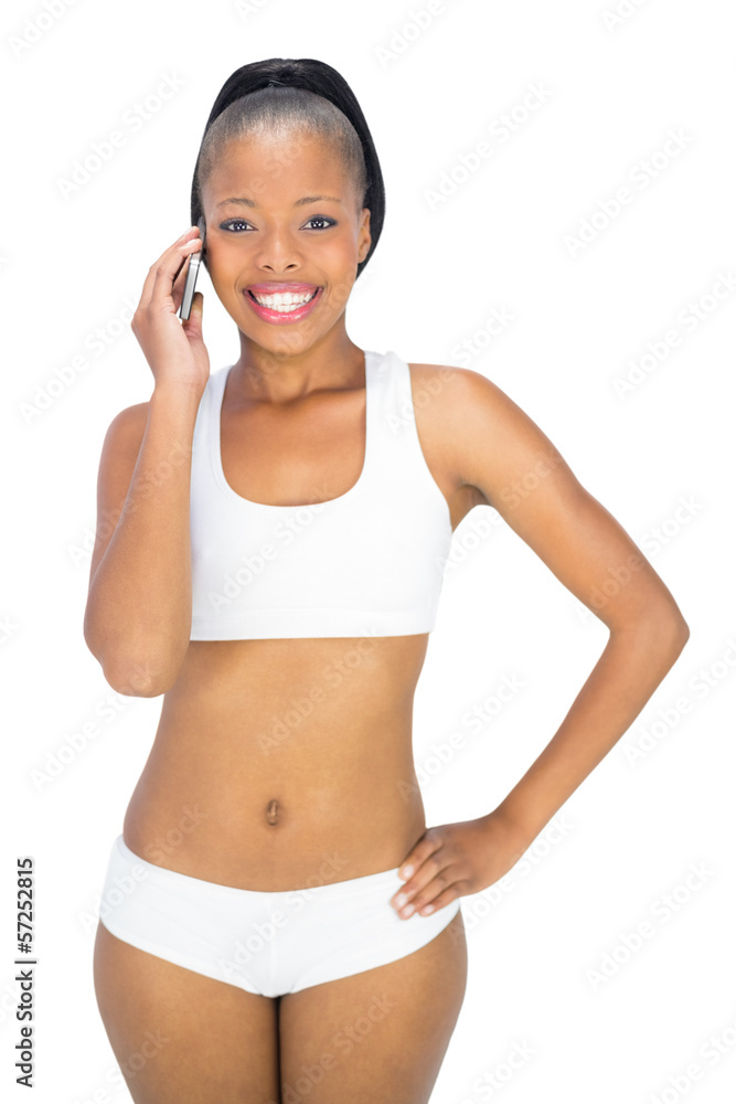 Fit woman in sportswear talking on phone while smiling at camera Fit woman in sportswear talking on phone while smiling at camera