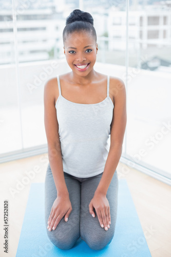 Happy woman sitting on blue exercise mat