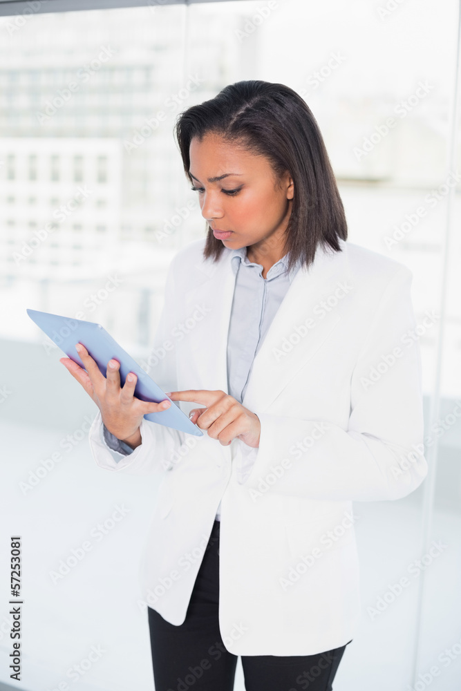 Thoughtful young dark haired businesswoman looking at her tablet Thoughtful young dark haired businesswoman looking at her tablet