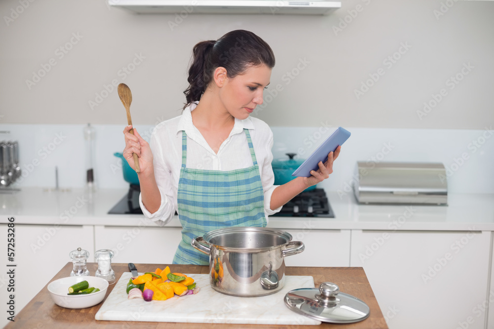 © lightwavemedia - Focused gorgeous woman wearing apron using tablet while cooking © lightwavemedia - Focused gorgeous woman wearing apron using tablet while cooking