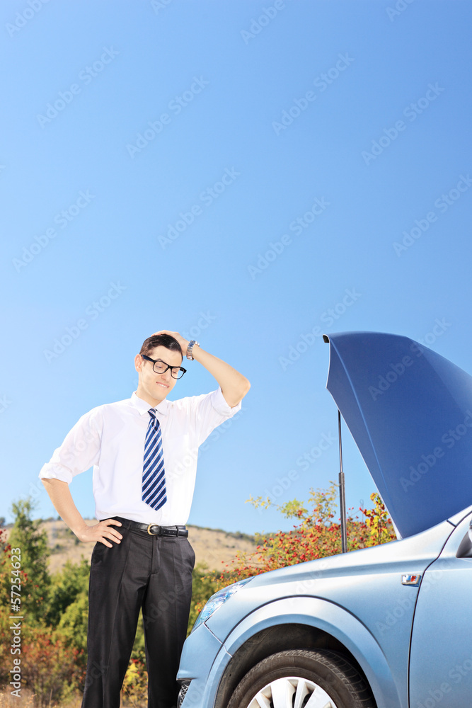 Confused man near a broken car thinking what to do