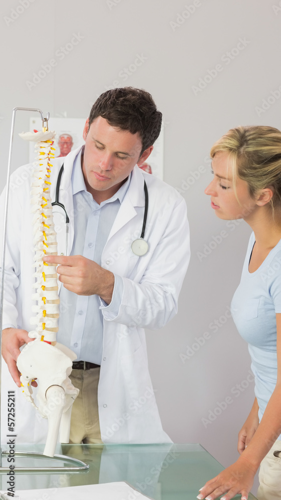 Fototapeta premium Serious doctor showing a patient something on skeleton model