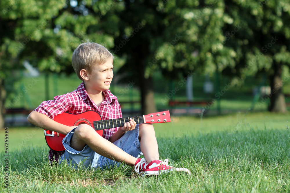boy sitting on grass and play guitar boy sitting on grass and play guitar