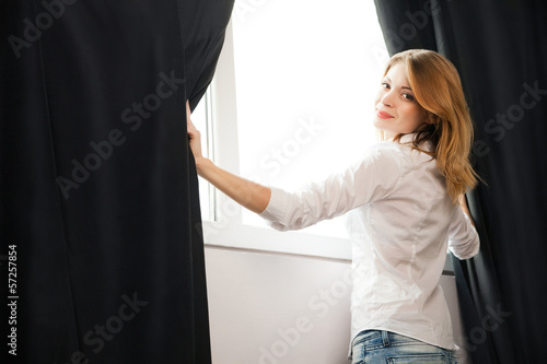 Girl opens the curtains and relaxing in morning