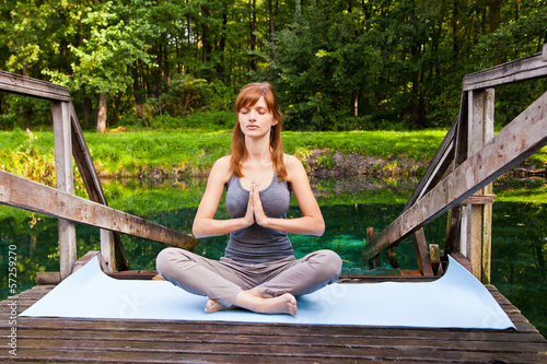 Young girl doing yoga (lotus pose) in the park © julenochek