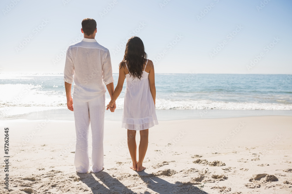 Attractive couple holding hands and watching the waves Attractive couple holding hands and watching the waves