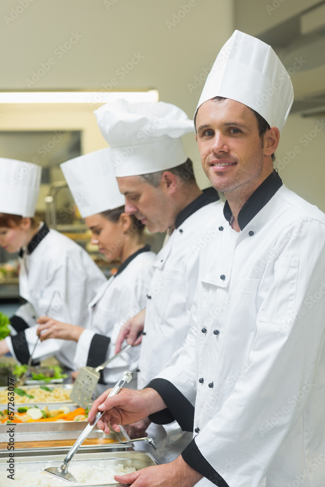 Happy chef standing at serving tray