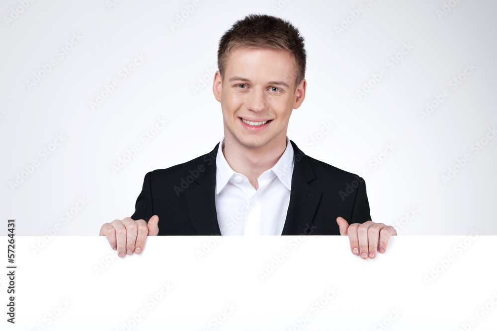 Smiling businessman standing behind the blank poster. Smiling businessman standing behind the blank poster.
