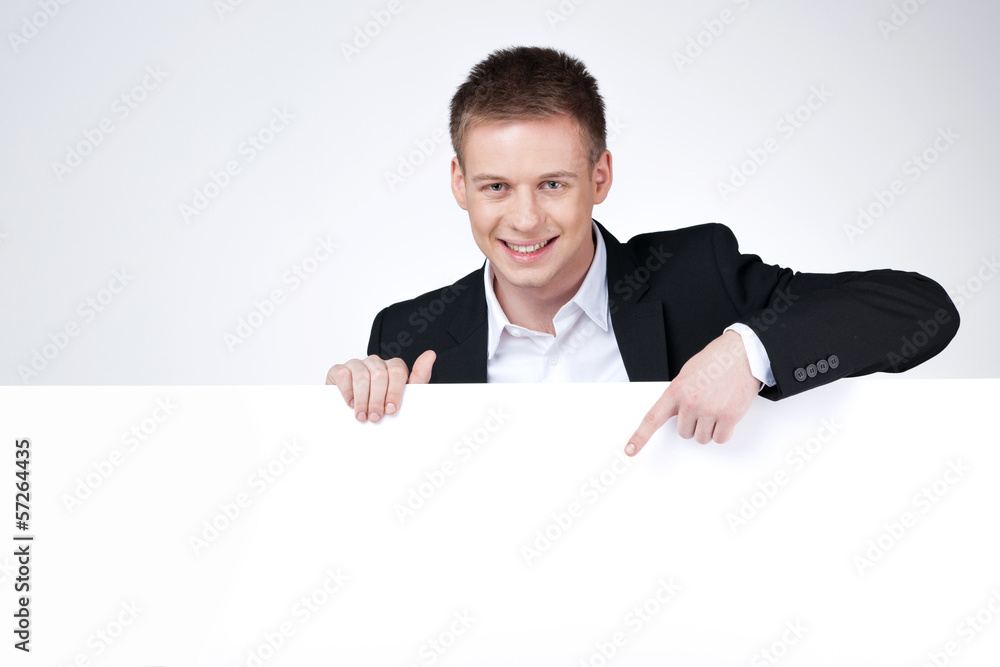 Handsome business man pointing with finger on blank poster. Handsome business man pointing with finger on blank poster.