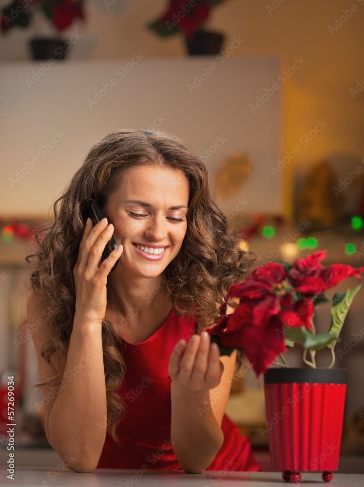 Smiling housewife talking phone and playing with christmas rose Smiling housewife talking phone and playing with christmas rose