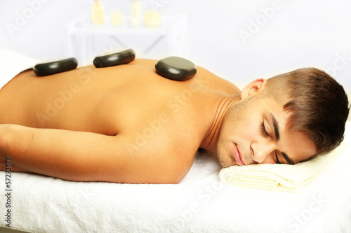 Young man relaxing with hot stones on back before massage