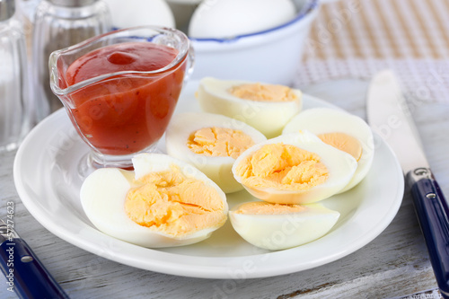 Boiled eggs on plate on wooden board on tablecloth