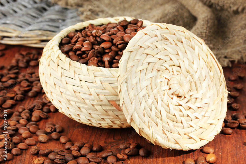 Coffee beans in wicker basket on wooden background