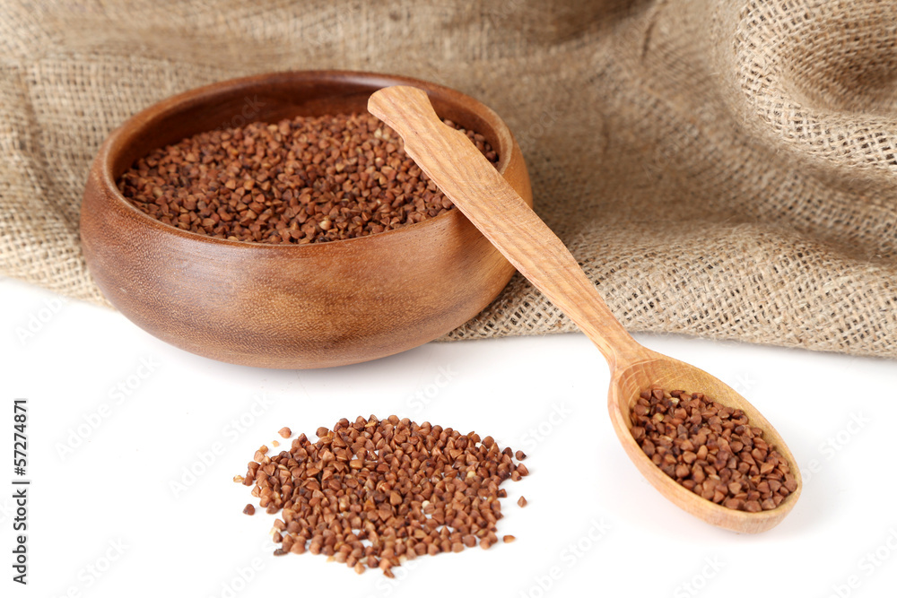 Buckwheat groats in bowl and wooden spoon isolated on white Buckwheat groats in bowl and wooden spoon isolated on white